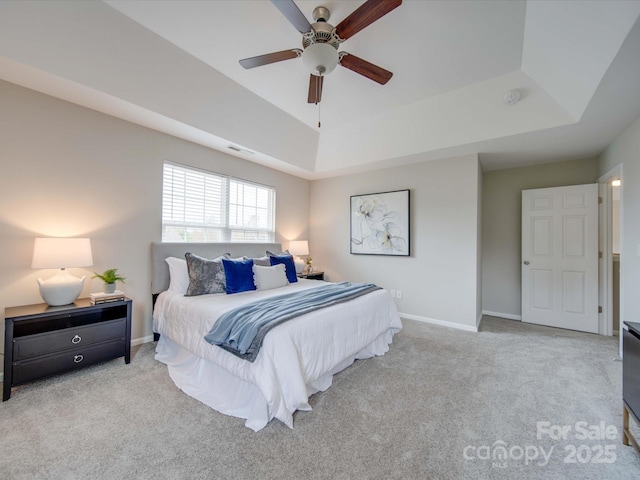 bedroom with ceiling fan, light carpet, and a tray ceiling