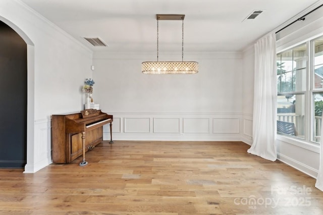 dining area featuring arched walkways, visible vents, and crown molding