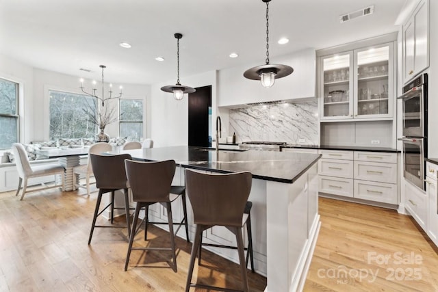 kitchen with dark countertops, glass insert cabinets, white cabinets, and a sink