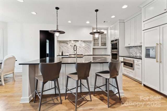 kitchen featuring a breakfast bar area, dark countertops, white cabinets, and pendant lighting