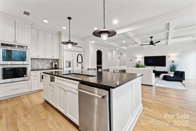 kitchen featuring dark countertops, white cabinets, a sink, and arched walkways