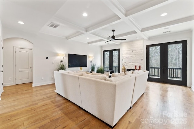 living area featuring french doors, light wood finished floors, visible vents, coffered ceiling, and beamed ceiling