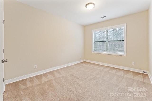 spare room featuring light colored carpet, visible vents, and baseboards