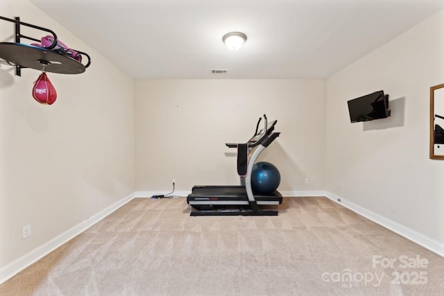 exercise room featuring baseboards, visible vents, and light colored carpet