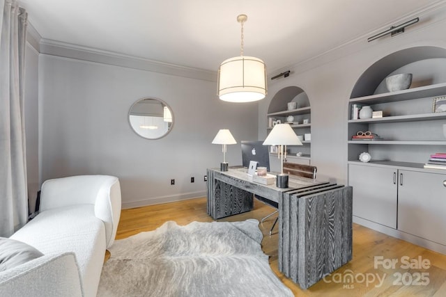 office space featuring ornamental molding, light hardwood / wood-style floors, and built in shelves