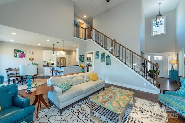 living room featuring an inviting chandelier, a towering ceiling, and light wood-type flooring