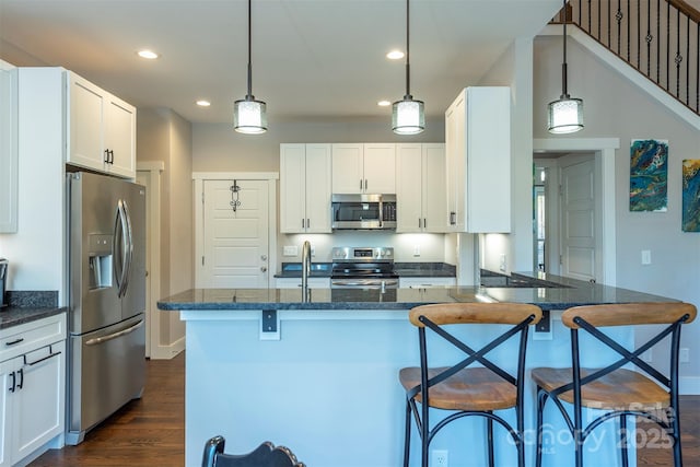 kitchen featuring decorative light fixtures, a kitchen breakfast bar, white cabinets, and appliances with stainless steel finishes