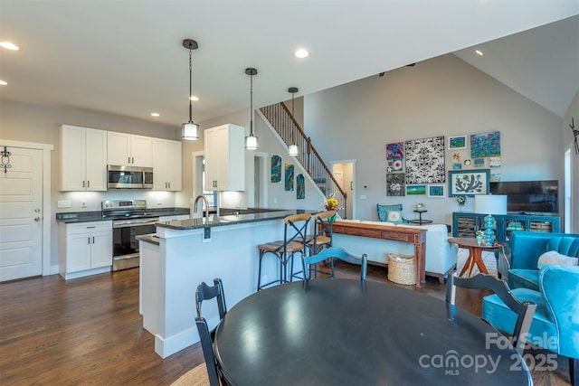 kitchen featuring pendant lighting, appliances with stainless steel finishes, white cabinets, a kitchen bar, and kitchen peninsula