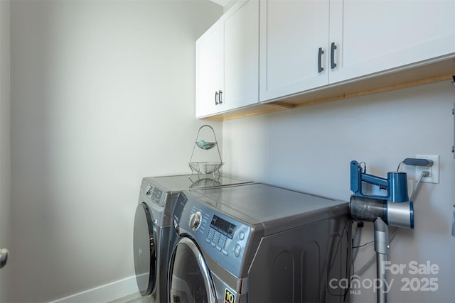 clothes washing area featuring separate washer and dryer and cabinets