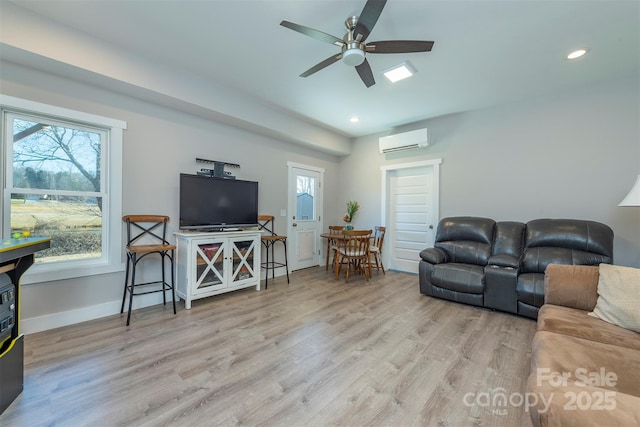 living room featuring a wall mounted air conditioner, light hardwood / wood-style floors, and ceiling fan