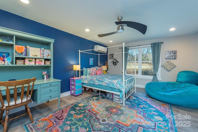 bedroom with wood-type flooring, a wall unit AC, and ceiling fan