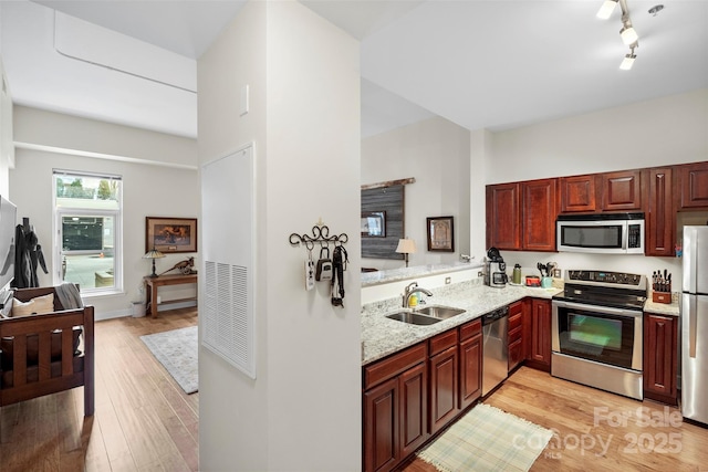 kitchen with sink, appliances with stainless steel finishes, light hardwood / wood-style flooring, and kitchen peninsula