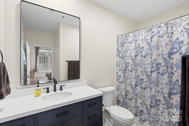 bathroom featuring toilet, vanity, and a shower with curtain