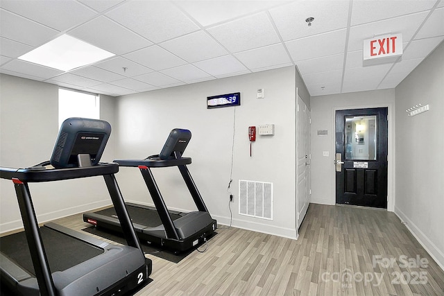 exercise room with light hardwood / wood-style floors and a drop ceiling