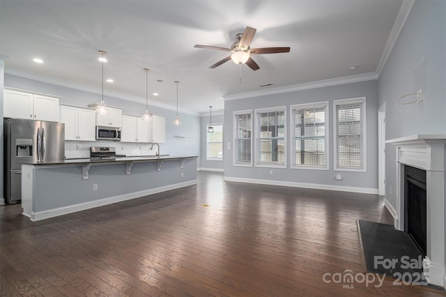 unfurnished living room featuring ceiling fan, sink, dark hardwood / wood-style flooring, and ornamental molding