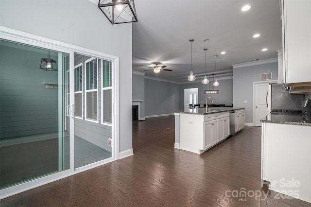 kitchen with ceiling fan, stainless steel dishwasher, white cabinets, pendant lighting, and an island with sink