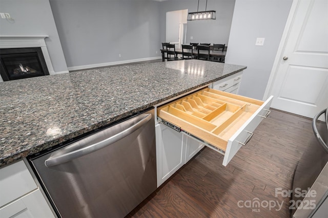 kitchen featuring white cabinetry, stainless steel dishwasher, dark stone countertops, pendant lighting, and dark hardwood / wood-style floors