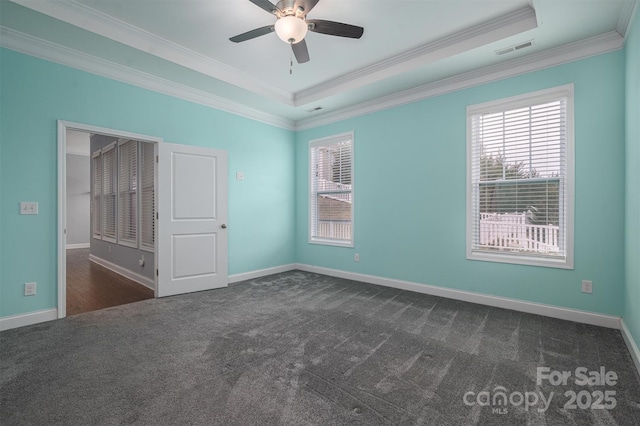 unfurnished room featuring dark colored carpet, a tray ceiling, and ornamental molding