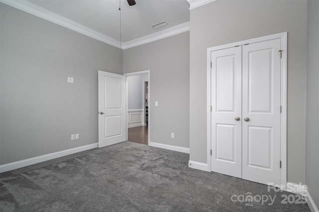 unfurnished bedroom featuring a closet, ceiling fan, dark colored carpet, and crown molding