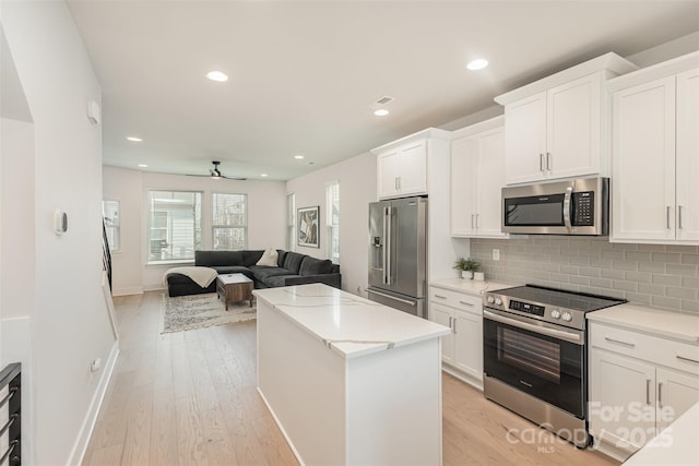 5048 York Park Ln, Charlotte, NC 28217 - kitchen with open floor plan, stainless steel appliances, a center island, backsplash, and white cabinets