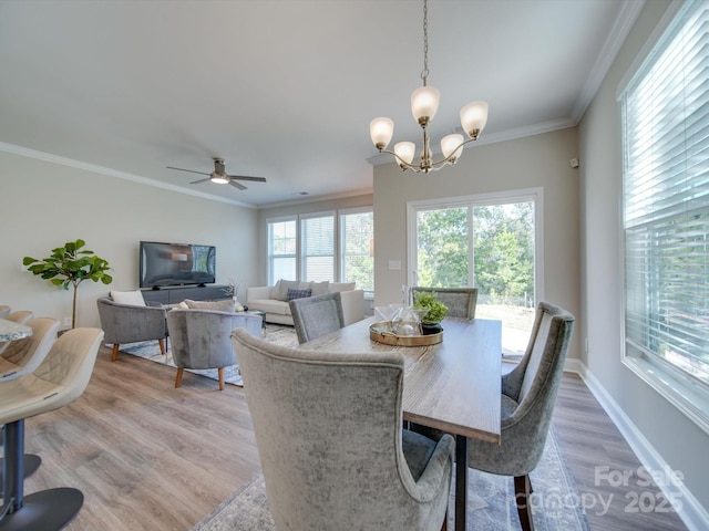 dining area featuring wood-type flooring, a healthy amount of sunlight, ceiling fan with notable chandelier, and ornamental molding