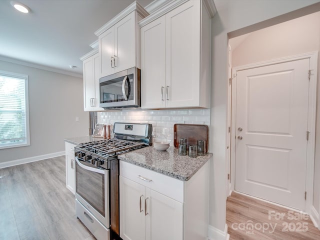 kitchen with light stone countertops, white cabinets, appliances with stainless steel finishes, backsplash, and light hardwood / wood-style flooring