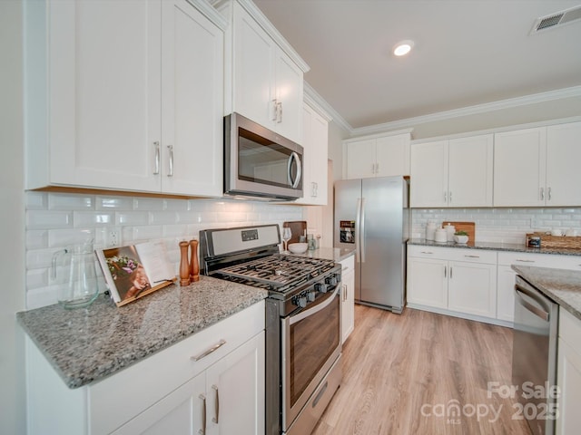 kitchen with white cabinetry, decorative backsplash, light stone countertops, and appliances with stainless steel finishes