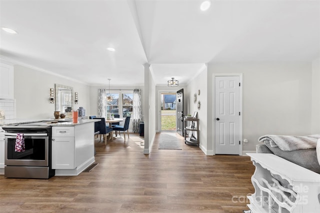 kitchen with white cabinetry, hardwood / wood-style floors, electric range, ornamental molding, and decorative light fixtures