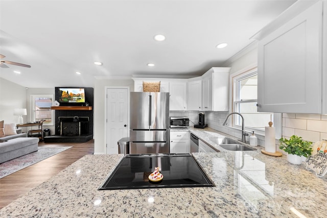 kitchen with stainless steel appliances, light stone countertops, sink, and white cabinets