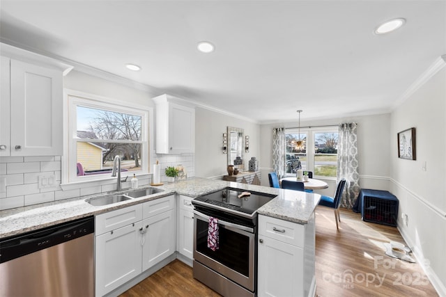 kitchen with sink, crown molding, appliances with stainless steel finishes, white cabinetry, and kitchen peninsula