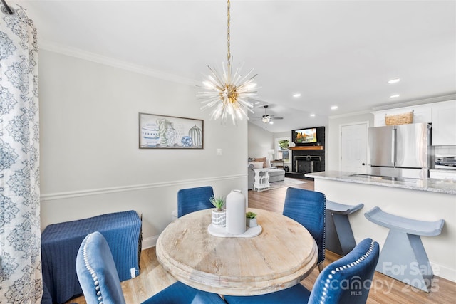 dining room featuring crown molding, ceiling fan with notable chandelier, and light hardwood / wood-style floors