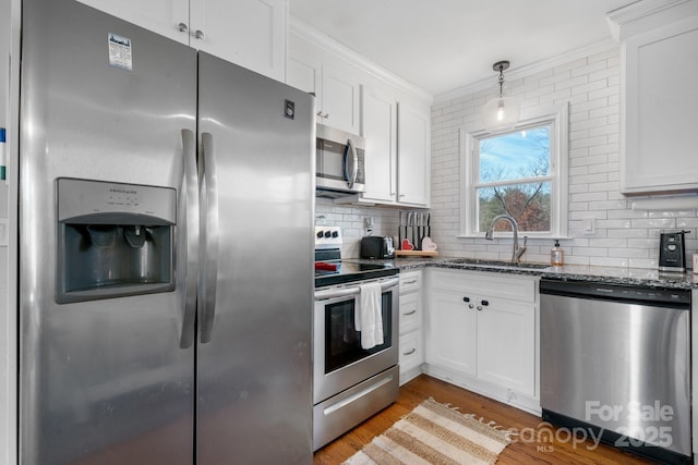 kitchen with dark stone countertops, stainless steel appliances, sink, and white cabinets