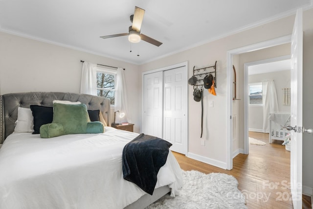 bedroom with multiple windows, ornamental molding, light hardwood / wood-style floors, and a closet