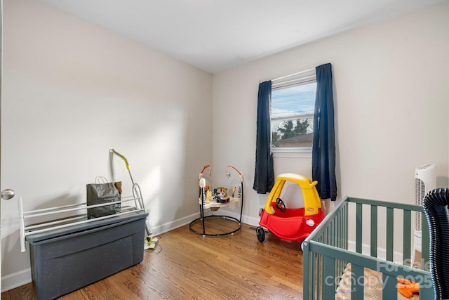 bedroom with hardwood / wood-style flooring and a crib