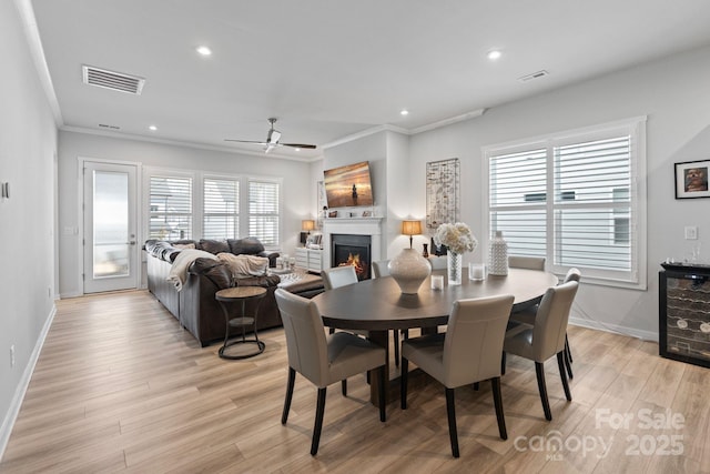 dining area with ceiling fan, ornamental molding, light hardwood / wood-style floors, and wine cooler