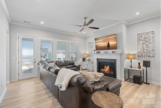 living room with light wood-type flooring, ceiling fan, and ornamental molding