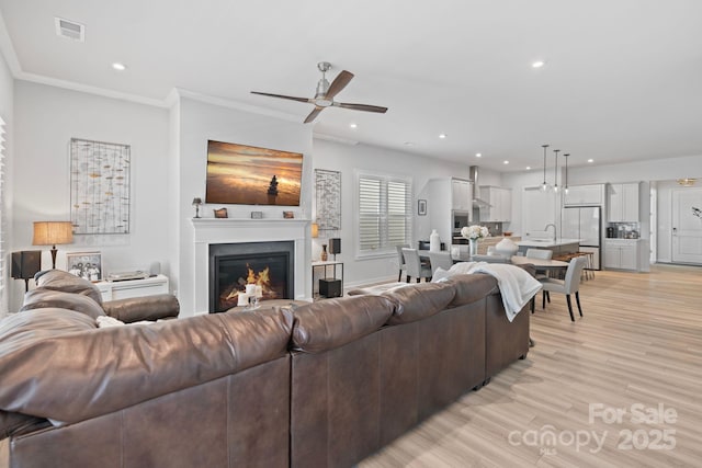 living room featuring ceiling fan, crown molding, and light hardwood / wood-style floors