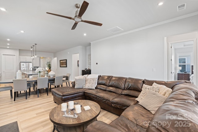 living room with ceiling fan, light hardwood / wood-style floors, and crown molding