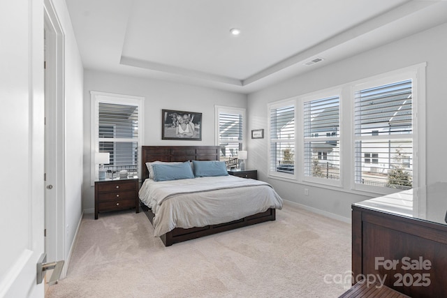 bedroom featuring a tray ceiling and light colored carpet