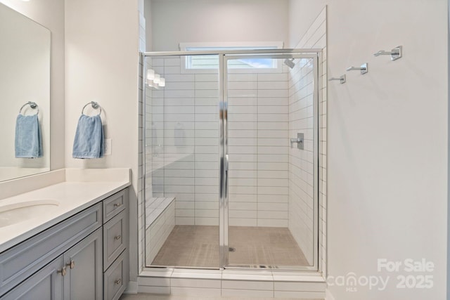 bathroom featuring a shower with door and vanity