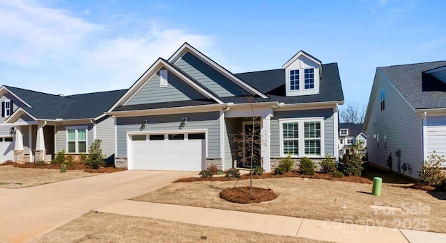 craftsman-style home featuring stone siding, an attached garage, and driveway