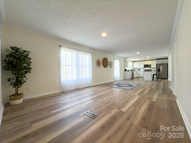 unfurnished living room featuring ornamental molding, a textured ceiling, and light hardwood / wood-style flooring