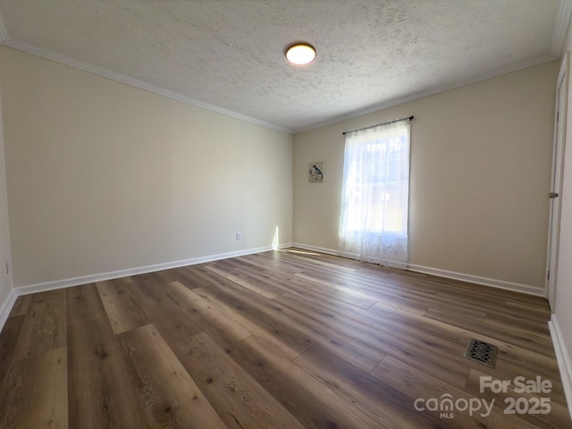 empty room with crown molding, dark hardwood / wood-style floors, and a textured ceiling