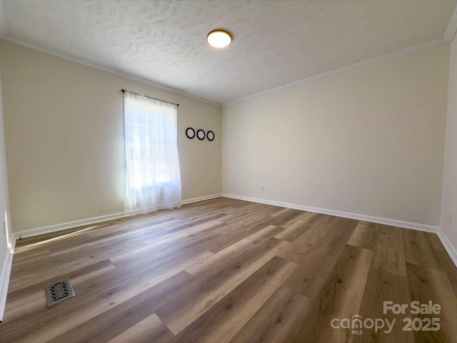 empty room with wood-type flooring, ornamental molding, and a textured ceiling