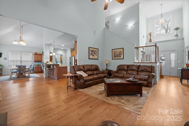 living room featuring ceiling fan, light hardwood / wood-style flooring, a high ceiling, and ornamental molding