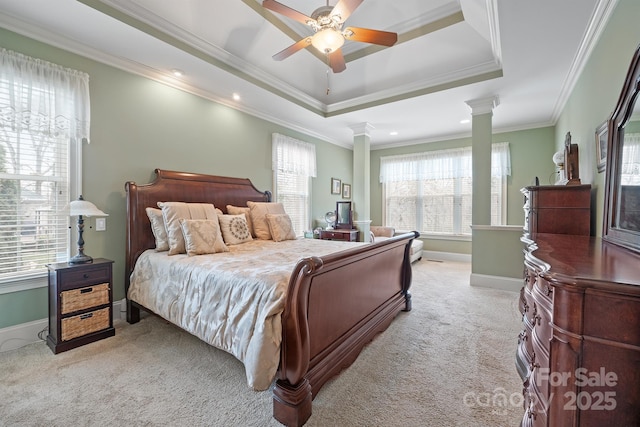 bedroom featuring light carpet, ceiling fan, ornamental molding, a raised ceiling, and decorative columns