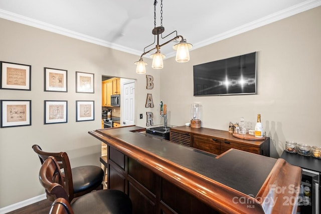 bar featuring dark wood-type flooring, crown molding, dark brown cabinets, appliances with stainless steel finishes, and pendant lighting