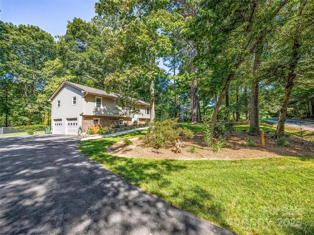 view of front of property featuring aphalt driveway, a front yard, brick siding, and an attached garage