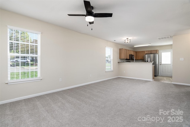 unfurnished living room featuring light carpet, a healthy amount of sunlight, and ceiling fan