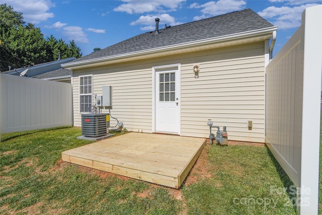 rear view of property with central air condition unit, a wooden deck, and a yard